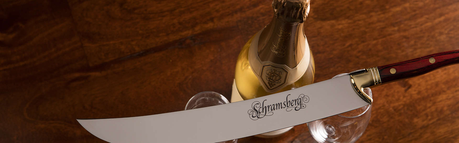 Corporate Gift Set. An overhead shot of a bottle and two glasses. On top of the glasses lays a Schramsberg logo saber