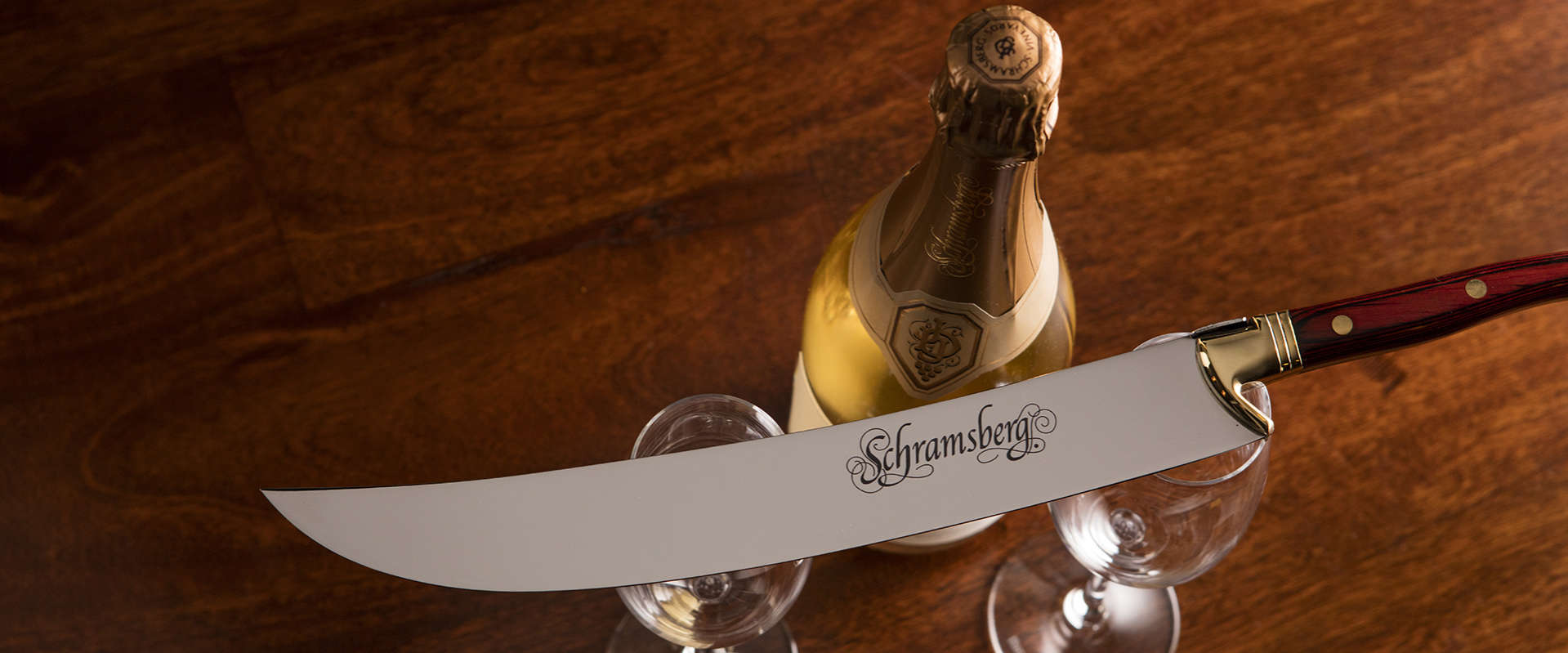 Corporate Gift Set. An overhead shot of a bottle and two glasses. On top of the glasses lays a Schramsberg logo saber