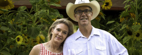 Hugh and Monique Davies toasting with wine in front of sunflowers