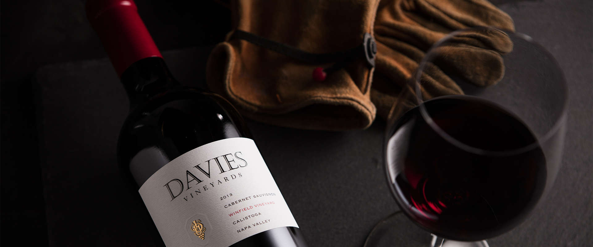 Davies Vineyards 2015 Winfield Vineyard Cabernet Sauvignon on a table with leather work gloves