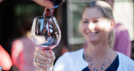 Smiling guest being poured a glass of Davies Vineyards red wine at a winery event.