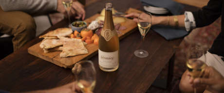 People around a coffee table enjoying Schramsberg Blancs de Noirs sparkling wine paired with a charcuterie board.