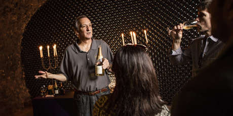 Wine educator discussing Schramsberg sparkling wine with guests by candlelight in historic wine caves.